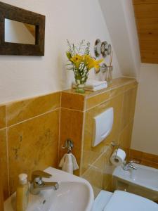 Un baño con un lavabo y un jarrón de flores amarillas. en Urlaub im alten E-Werk, en Görisried