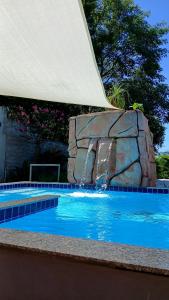 a swimming pool with a waterfall and a rock at Hostel Sossego do Garças in Barra do Garças