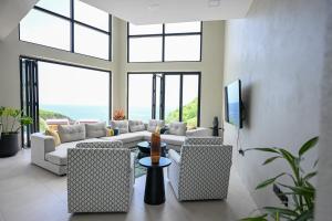 Una sala de estar con un sofá y sillas y ventanas. en Villa Jasiri, en Gros Islet