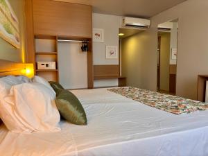 a bedroom with a large white bed with pillows at Flat Executivo in Fórum Manaus - BlueTree in Manaus