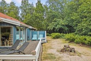 ein blaues Haus mit Stühlen auf einer Holzterrasse in der Unterkunft 1474 Aakirkeby - Boesparken 20 in Vester Sømarken