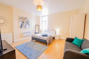 una sala de estar con un sofá y una cama en Spacious Modern & High Ceiling One Bedroom Apartment, en Cardiff