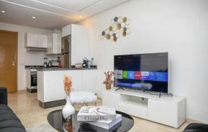 a living room with a large tv and a kitchen at Appart luxe arya in Fès