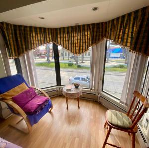 a room with a large window with a chair and a table at Karol Hostal in Punta Arenas