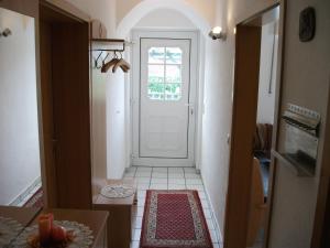 un couloir avec une porte blanche et du carrelage. dans l'établissement Ferienwohnung Am Bach, à Rees