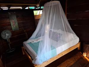 a bed with a mosquito net in a room at Mangle House Cabañas Ladrilleros in Buenaventura