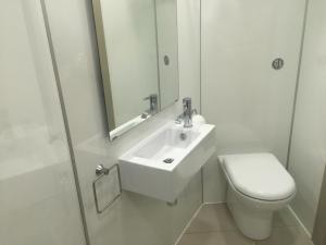 Baño blanco con lavabo y aseo en The Harbour Guest House en Irvine