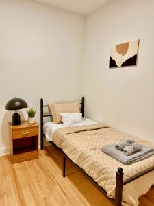 a bedroom with a bed and a lamp and a table at Spacious 3BR Apartment - 12min Newark Airport -Near NYC & Malls in Newark