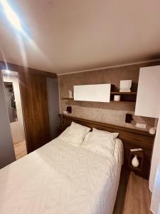 a bedroom with a white bed with a wooden headboard at Magnifique Mobil home avec vue in Lège-Cap-Ferret
