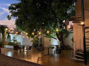 a patio with tables and chairs under a tree at AZUL ARENA Hotel Boutique in Mazatlán