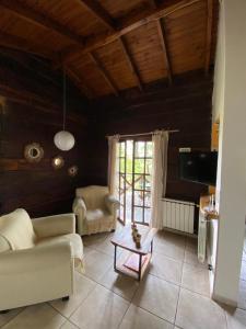Una sala de estar con un sofá y un televisor. en Cabañas Ruca Alihuen, en La Cumbrecita