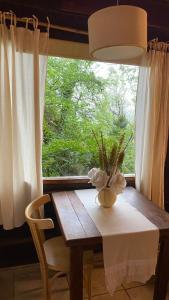 una mesa con un jarrón en ella con una ventana en Cabañas Ruca Alihuen, en La Cumbrecita