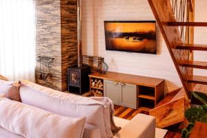 a living room with a couch and a tv on a wall at Chalé cruzeiro do sul, hidromassagem, 2 min Thermas Machadinho-RS #2 in Machadinho