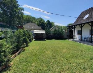 une cour avec une maison et un jardin avec des arbres dans l'établissement Avanti Apartman - Avanti Top, à Balatonboglár