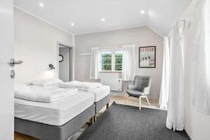 a white bedroom with two beds and a chair at 6727-Hasle-Udmarksvej-10 in Hasle