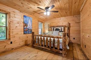 a log cabin bedroom with a bed and a ceiling fan at Willow Falls in Blue Ridge