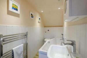 a bathroom with a sink and a bath tub at Hemingford Cottage in Brancaster +11 photos