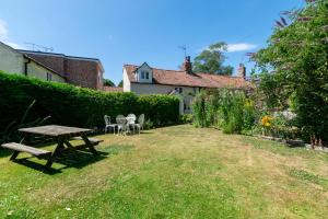 einen Garten mit einem Picknicktisch und Stühlen im Gras in der Unterkunft Dale Cottage in East Rudham