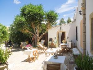 a patio with tables and chairs and a palm tree at B&B Le Macine 1868 in Paceco