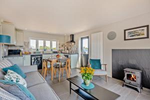 Swallows Return - Colkirk في Colkirk: غرفة معيشة مع أريكة وطاولة مع موقد