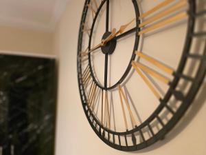 a black and gold clock hanging on a wall at North London Holiday home, Driveway Parking, BBQ and Indoor Jacuzzi hot tub in Brimsdown Station
