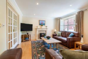 un salon avec un canapé en cuir et une cheminée dans l'établissement Mallard Cottage, à Blakeney