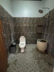 a bathroom with a toilet and a sink and a tub at Maluk kost Tika HomeStay in Maluk