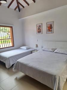 two beds in a white room with a window at Casa Nueva en Zapatoca in Zapatoca