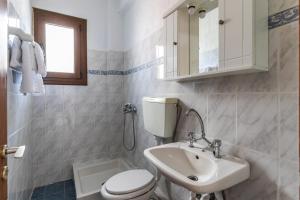 a bathroom with a white toilet and a sink at Fotini Rooms in Skopelos Town