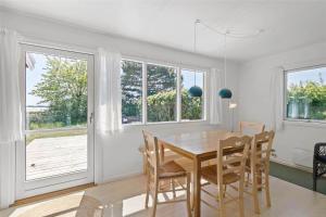 Un comedor con mesa y sillas y ventanas. en 3663-Nexo-Strandvolden-3, en Neksø 14 fotos más