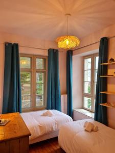 two beds in a room with two windows at Grande maison familiale les pieds dans l'eau in Ploubazlanec