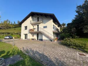 a white house with a balcony and a driveway at Casa vacanze Ai Denat in Lamon