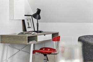 a red chair sitting next to a desk with a lamp at 4790-Ronne-Kanegardsvej-12-1 in Rønne