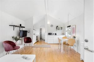 eine weiße Küche und ein Esszimmer mit Tisch und Stühlen in der Unterkunft 6788 Allinge - Gyvelvej 11 A in Allinge