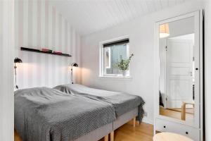 ein weißes Schlafzimmer mit einem Bett und einem Spiegel in der Unterkunft 6788 Allinge - Gyvelvej 11 A in Allinge