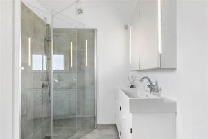 ein weißes Badezimmer mit Waschbecken und Dusche in der Unterkunft 6788 Allinge - Gyvelvej 11 A in Allinge + 17 Fotos
