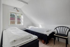 two beds in a room with a chair and a window at 6736-Allinge-Thorkildsvej-8 in Allinge