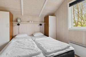 una cama en una habitación con ventana en 1436-Aakirkeby-Strandlokken-10, en Vester Sømarken