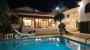 a swimming pool in front of a house at night at Sítio Chamego - RJ in Engenheiro Paulo de Frontin