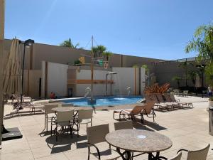 Un patio con mesas y sillas y una piscina. en Boulevard Suítes Host Hub, en Caldas Novas