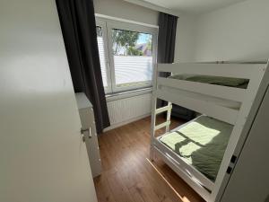 a room with two bunk beds and a window at Vier Nordlichter Erdgeschosswohnung mit Terrasse und Garten in Bensersiel