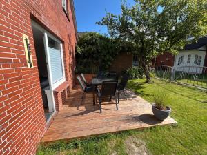 a wooden deck with chairs and a table in a yard at Vier Nordlichter Erdgeschosswohnung mit Terrasse und Garten in Bensersiel