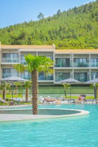 a pool with a palm tree in front of a hotel at Thassos Imperial Resort in Skala Rachoniou