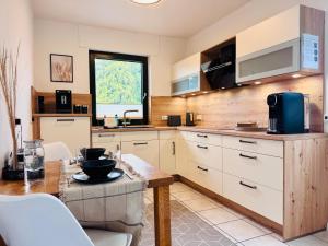 a kitchen with white cabinets and a table at Stylisches modernes Apartment, Sauna und Wellness Top Lage in Lübbecke