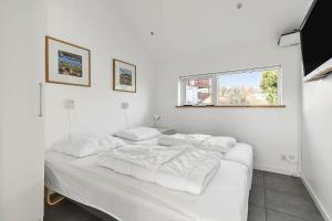 a white bedroom with two beds and a window at 6663-Allinge-Stien-4 in Allinge