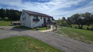 a small white house with a porch and a driveway at MV Vacances in Les Rousses