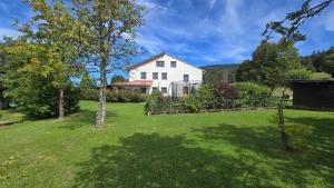 a white house with a yard with green grass at MV Vacances in Les Rousses