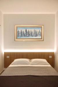 un quadro di alberi su una parete sopra un letto di Hotel Brivio a Milano