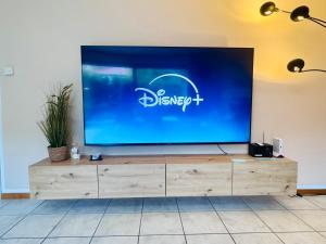 a large screen tv sitting on top of a wooden dresser at Stylisches modernes Apartment, Sauna und Wellness Top Lage in Lübbecke +35 photos