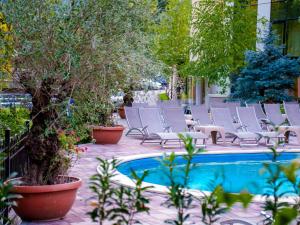a group of chairs sitting next to a pool at Hotel IZVOARE Caciulata in Călimăneşti